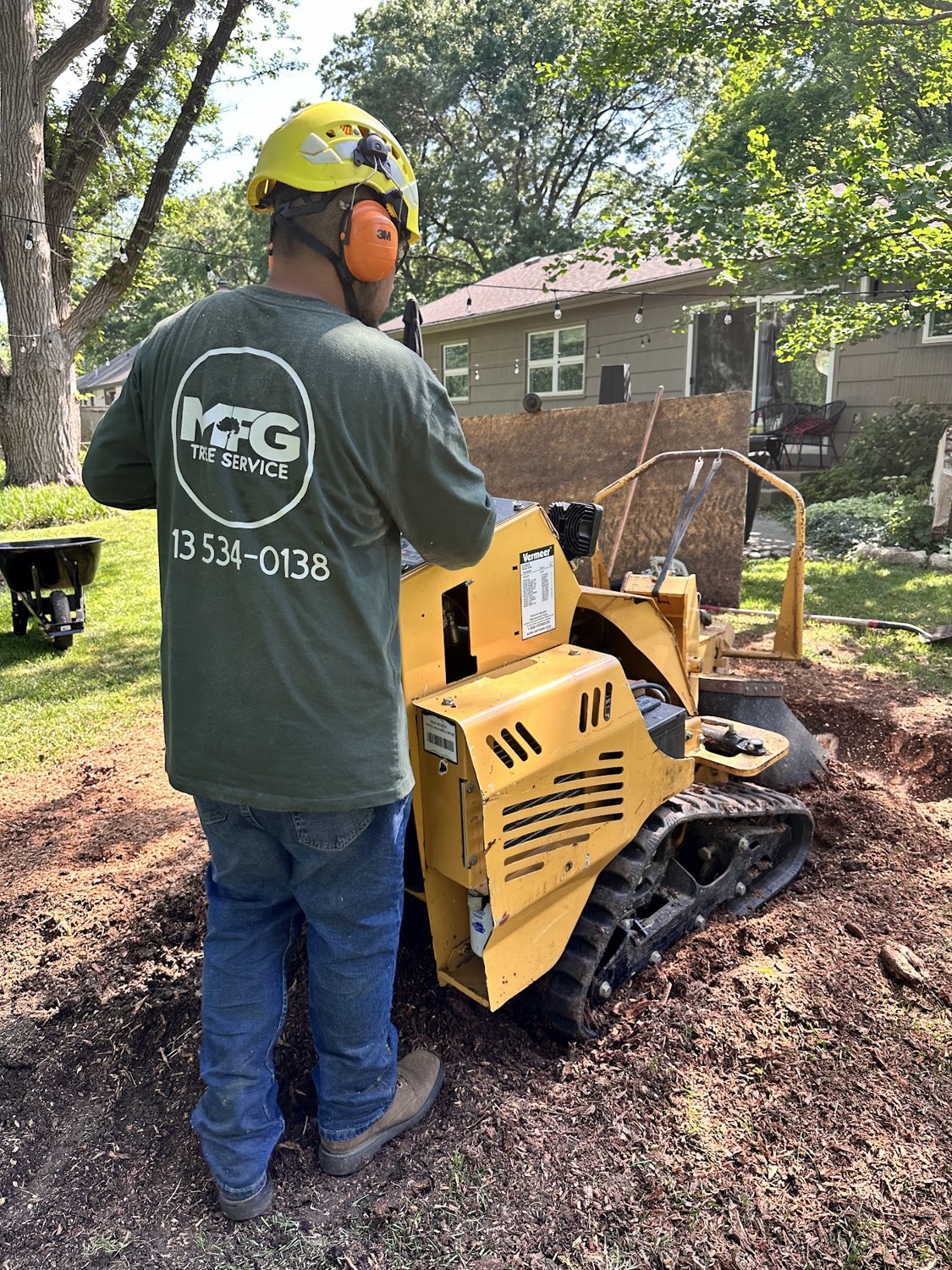 MFG Tree Service crew member operating a stump grinder on a job